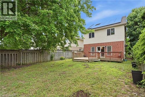 Expansive backyard featuring a multi-level wood-finish deck, brick and siding exterior, solar panels, and mature perimeter trees - 128 Houghton Street, Cambridge, ON 