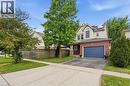 Brick and siding exterior featuring an arched window, attached garage, solar panels, and mature trees - 128 Houghton Street, Cambridge, ON  - Outdoor 