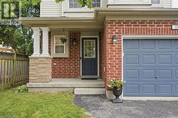 Brick facade with stone veneer porch columns, covered entryway, and a paneled garage door - 