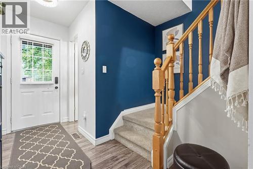 Entryway featuring a white door with an integrated window and horizontal blinds, wood-finish flooring, and a staircase with light wood banister and balusters - 128 Houghton Street, Cambridge, ON - Indoor Photo Showing Other Room