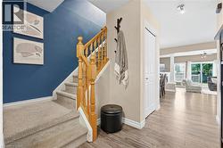 Entryway featuring wood-finish flooring, a carpeted staircase with wood banister, and a white paneled door - 