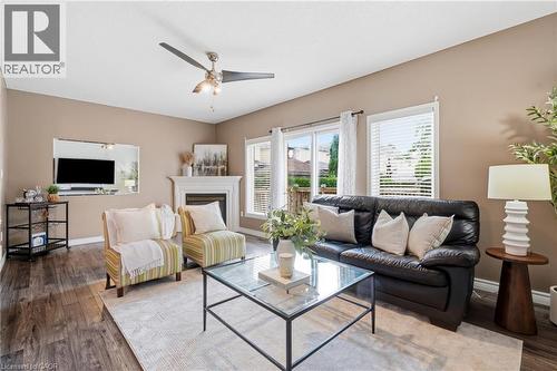 Spacious living area featuring wood-finish flooring, a fireplace with a mantel, multiple windows, and a ceiling fan - 128 Houghton Street, Cambridge, ON - Indoor Photo Showing Living Room
