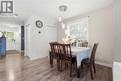 Dining area featuring wood-finish flooring, a contemporary pendant light fixture, and a window with blinds - 