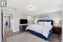 Spacious bedroom with wood-finish flooring, light grey wall paint, and a textured ceiling - 