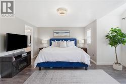 Spacious room featuring wood-finish flooring, a contemporary ceiling fixture, and neutral wall tones - 