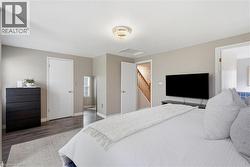 Bedroom featuring wood-finish flooring, neutral wall tones, and a contemporary ceiling fixture - 