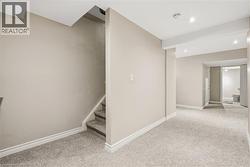 Recessed lighting illuminates a spacious carpeted area with neutral-toned walls and white baseboards - 