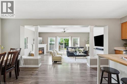 Open-concept living area with wood-finish flooring, a fireplace with white mantle, and a ceiling fan - 128 Houghton Street, Cambridge, ON 