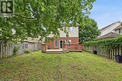 Expansive rear yard featuring a multi-level wood deck, red brick and siding exterior, and mature perimeter trees - 