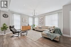 Spacious living area featuring wood-finish flooring, recessed lighting, and a contemporary chandelier - 