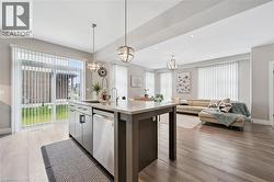 Open-concept living space with wood-finish flooring, recessed lighting, and large windows with vertical blinds - 