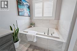 Built-in soaking tub with chrome fixtures, surrounded by light-toned tilework - 