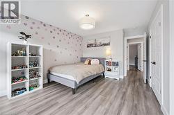 Spacious room featuring wood-finish flooring, a contemporary drum light fixture, and a neutral color palette - 