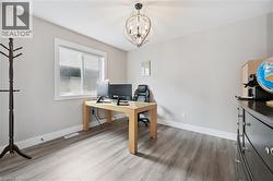 Spacious room featuring wood-finish flooring, a window with white trim, a decorative light fixture, and neutral wall tones - 