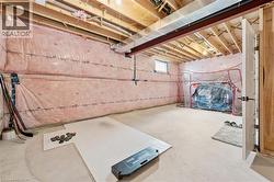 Spacious unfinished basement featuring exposed wood joists, concrete flooring, and insulated walls - 