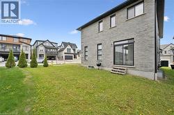 Grey brick exterior with multiple windows, featuring a sliding glass door with external steps leading to a green lawn - 