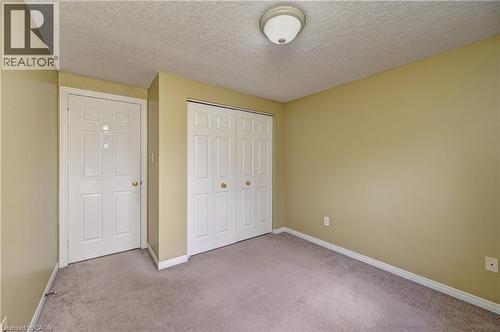 Carpeted room featuring a ceiling-mounted light fixture, two panel doors, and neutral wall paint - 760 Paris Boulevard, Waterloo, ON 