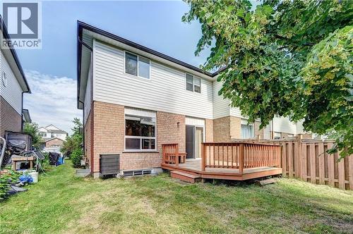 Rear exterior featuring a wood deck, brown brick lower facade, white siding upper facade, and a sliding glass door - 760 Paris Boulevard, Waterloo, ON 
