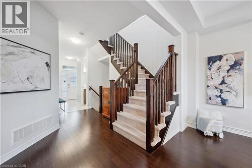 Grand staircase featuring dark wood newel posts and balusters, carpeted treads, and a rich wood-finish flooring - 87 Ridge Road, Cambridge, ON 