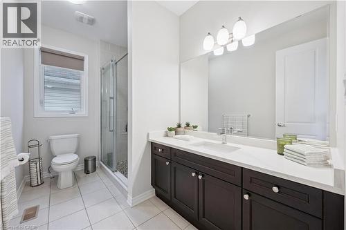 Contemporary bathroom featuring a dark wood-finish double vanity with a light-toned countertop, a built-in rectangular sink, and an expansive mirror - 87 Ridge Road, Cambridge, ON 