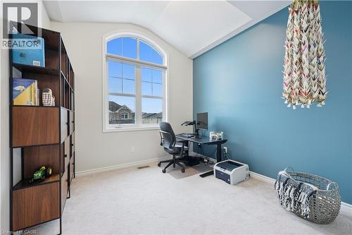 High vaulted ceiling with a prominent arched window, light-toned carpeting, and a built-in shelving unit featuring wood-finish panels and a dark metal frame - 87 Ridge Road, Cambridge, ON 