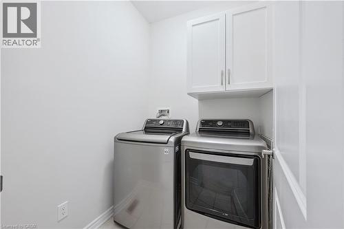 Dedicated laundry area featuring white shaker-style cabinetry, a built-in shelf, and baseboard trim - 87 Ridge Road, Cambridge, ON 