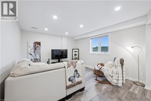Spacious living area featuring light gray walls, recessed lighting, and wood-finish flooring - 87 Ridge Road, Cambridge, ON 