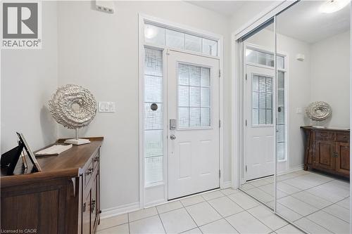 Entryway featuring a white door with decorative glass inserts and transom, accompanied by a full-length mirrored closet - 87 Ridge Road, Cambridge, ON 