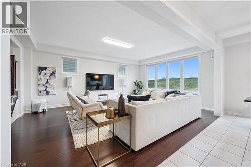 Spacious living area featuring large windows, dark wood-finish flooring, a contemporary ceiling light fixture, and light-colored walls - 87 Ridge Road, Cambridge, ON 