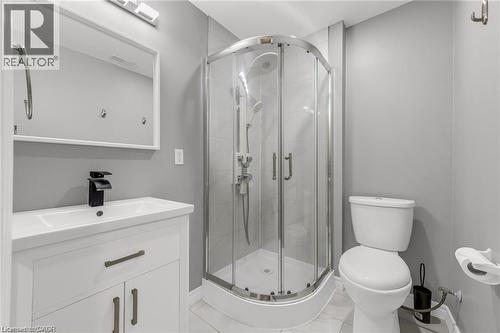 Bathroom featuring a curved glass shower enclosure, a white vanity with integrated sink and matte black faucet, and a wall-mounted mirror with overhead lighting - 8 Hemlock Way Unit# 22, Grimsby, ON 