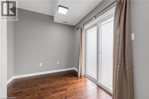 Sliding glass doors with window treatments, wood-finish flooring, and light gray wall paint - 8 Hemlock Way Unit# 22, Grimsby, ON 