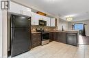 Kitchen featuring two-tone cabinetry with white upper and dark wood-finish lower units, a mosaic tile backsplash, and stone-finish countertops - 8 Hemlock Way Unit# 22, Grimsby, ON 