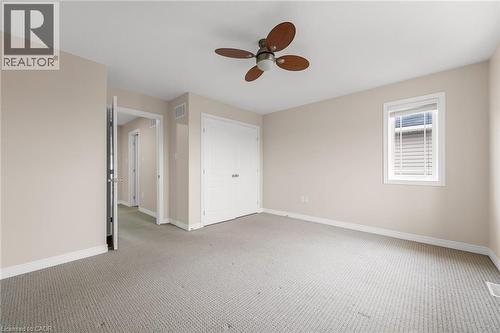 Spacious room featuring neutral carpeting, a dual-door closet, and a ceiling fan with wood-finish blades - 8 Hemlock Way Unit# 22, Grimsby, ON 