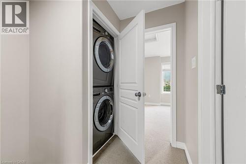 Dedicated laundry area featuring stacked dark-finish appliances - 8 Hemlock Way Unit# 22, Grimsby, ON 
