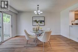Dining area featuring wood-finish flooring, a modern chandelier, and sliding glass doors to the exterior - 
