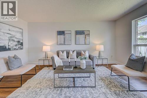 Living area featuring light neutral wall tones, wood-finish flooring, and a large window providing natural light - 139 Werstine Terrace, Cambridge, ON 