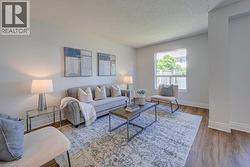 Living area featuring wood-finish flooring, white baseboards, and a large window with white trim - 