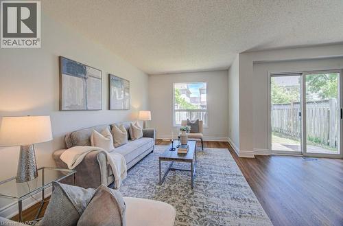 Open-concept living area featuring wood-finish flooring, a white trim baseboard, and a sliding glass door providing outdoor access - 139 Werstine Terrace, Cambridge, ON 