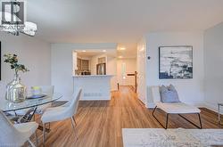 Open-concept living space featuring wood-finish flooring, a contemporary chandelier, and a breakfast bar pass-through to the kitchen - 