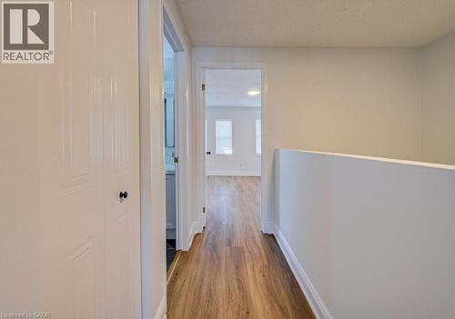 Hallway with wood-finish flooring, light neutral wall paint, and white trim - 139 Werstine Terrace, Cambridge, ON 