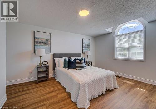 Room featuring an arched window, wood-finish flooring, white baseboards, and a flush-mount ceiling light - 139 Werstine Terrace, Cambridge, ON 
