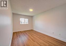 Room featuring wood-finish flooring, white baseboards, a white window frame, and a recessed ceiling light - 