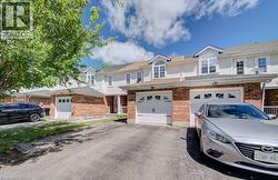 Exterior featuring brick and siding construction, dormer windows, attached garage, paved driveway, and mature tree - 