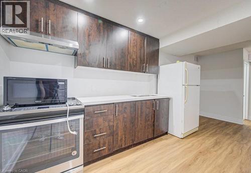 Kitchen featuring dark wood-finish cabinetry with silver hardware, light-toned countertops, a stainless steel range with overhead ventilation, and light wood-finish flooring - 139 Werstine Terrace, Cambridge, ON 