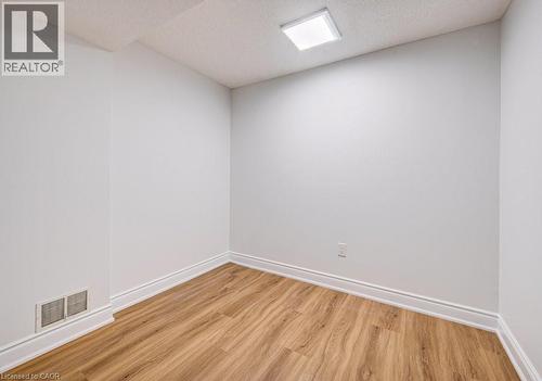 Room featuring wood-finish flooring, white walls, white baseboards, and a square ceiling light fixture - 139 Werstine Terrace, Cambridge, ON 