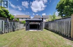 Expansive fenced backyard featuring a central gazebo with dark fabric screens - 