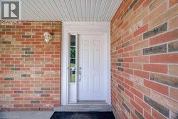 White paneled entry door with a sidelight, brick exterior, and a protective overhang with a soffit - 