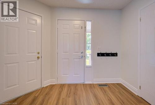 Entryway featuring wood-finish flooring, white paneled doors, and a vertical sidelight window - 139 Werstine Terrace, Cambridge, ON 