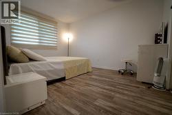 Spacious room featuring wood-finish flooring, white walls, and a large window with horizontal blinds - 