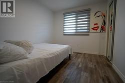 Bedroom featuring wood-finish flooring, a window with horizontal blinds, and a built-in closet with mirrored sliding doors - 
